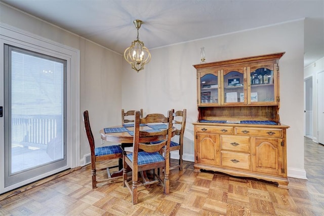 dining space with an inviting chandelier, baseboards, and ornamental molding