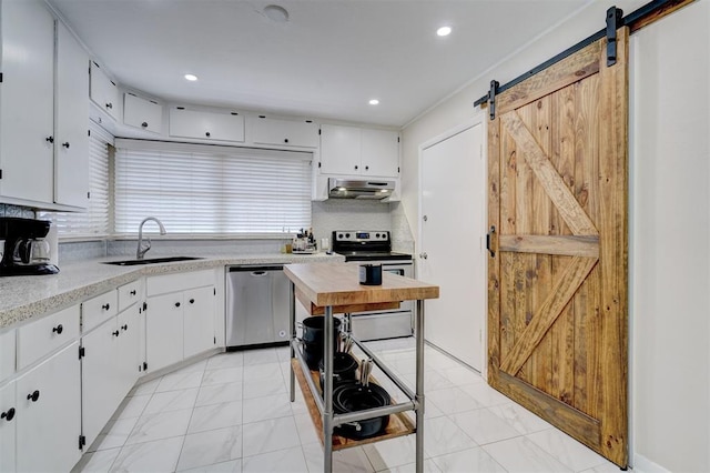 kitchen with a barn door, under cabinet range hood, stainless steel appliances, a sink, and light countertops