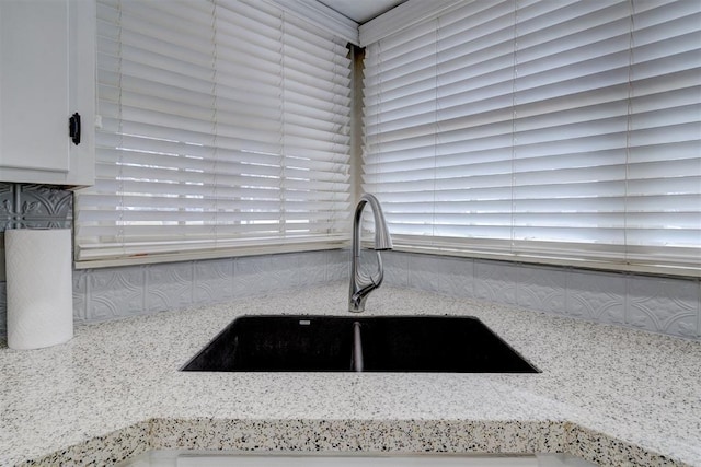 details with light stone counters, a sink, and white cabinets