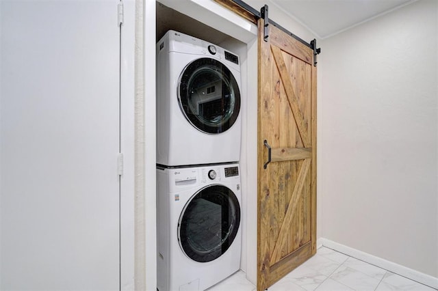 clothes washing area with stacked washer and clothes dryer, marble finish floor, a barn door, laundry area, and baseboards