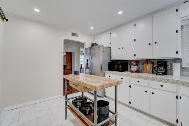 kitchen with visible vents, stainless steel fridge with ice dispenser, marble finish floor, light countertops, and black microwave