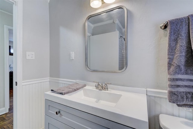 bathroom with toilet, a wainscoted wall, and vanity