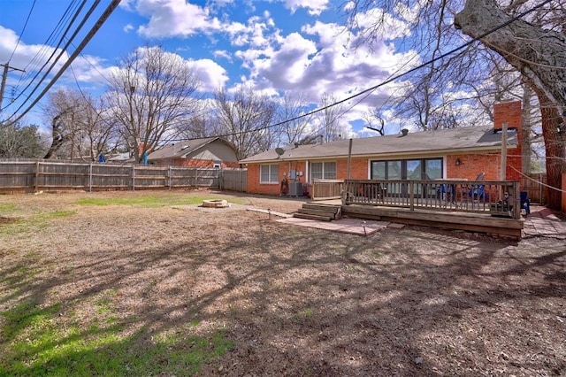 rear view of house with an outdoor fire pit, a fenced backyard, a chimney, a deck, and brick siding