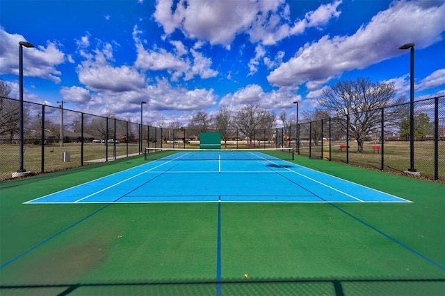 view of tennis court with community basketball court and fence