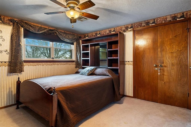 carpeted bedroom featuring a ceiling fan, visible vents, and a textured ceiling