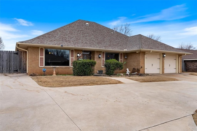 view of front of house featuring fence, concrete driveway, a shingled roof, a garage, and brick siding