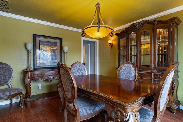 dining area with baseboards, wood finished floors, visible vents, and ornamental molding