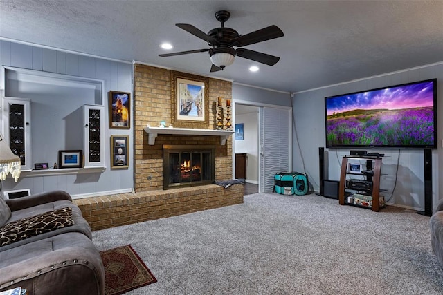 carpeted living area with a textured ceiling, recessed lighting, crown molding, a brick fireplace, and ceiling fan