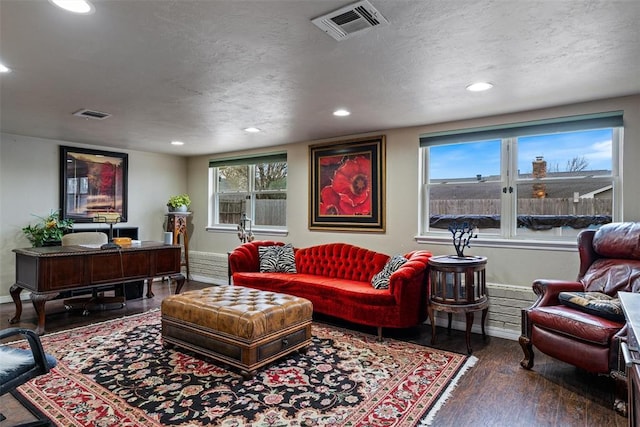 living area with wood finished floors, visible vents, and a healthy amount of sunlight