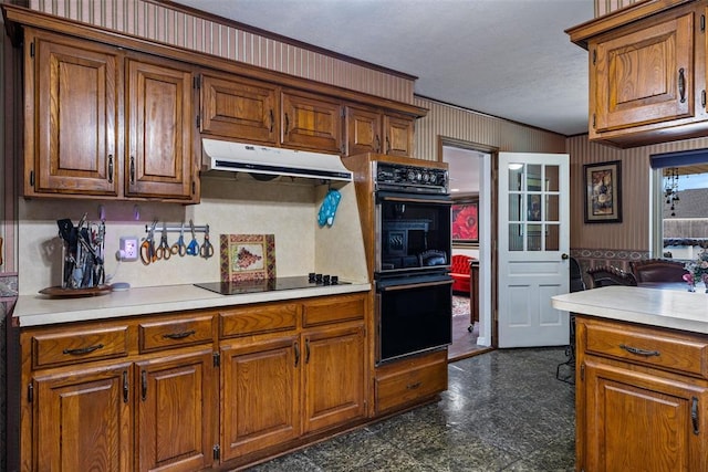 kitchen featuring black appliances, light countertops, brown cabinets, and under cabinet range hood