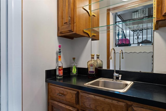 kitchen with a sink, brown cabinets, and dark countertops