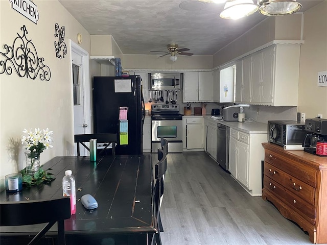 kitchen with a ceiling fan, white cabinets, light wood-style floors, light countertops, and appliances with stainless steel finishes