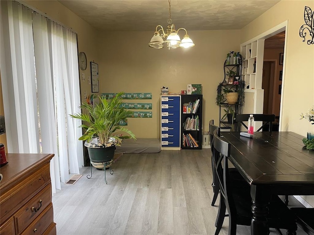 dining area with light wood finished floors and a chandelier