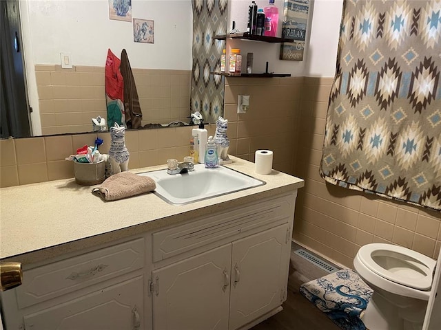 bathroom with tile walls, visible vents, vanity, and toilet