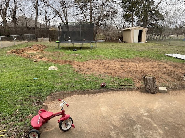 view of yard with a storage shed, a trampoline, an outdoor structure, and fence