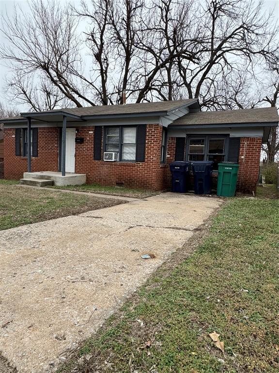 ranch-style house featuring brick siding, driveway, and a front lawn