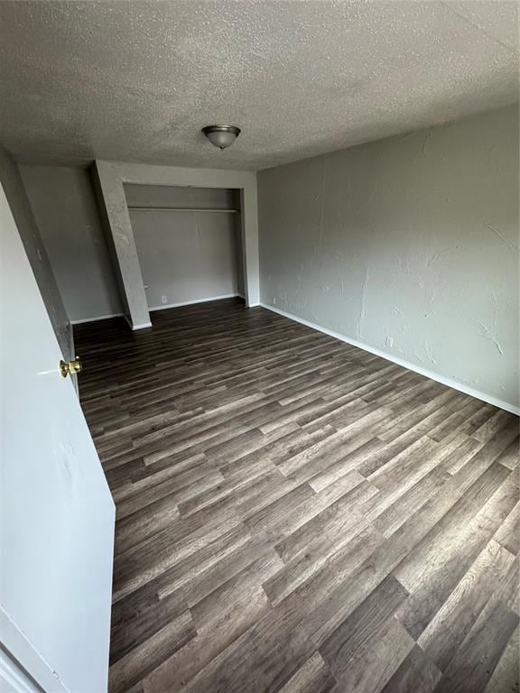 unfurnished bedroom with a textured ceiling, a closet, wood finished floors, and baseboards