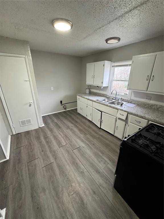 kitchen with black gas range, visible vents, dark wood-type flooring, white cabinetry, and a sink