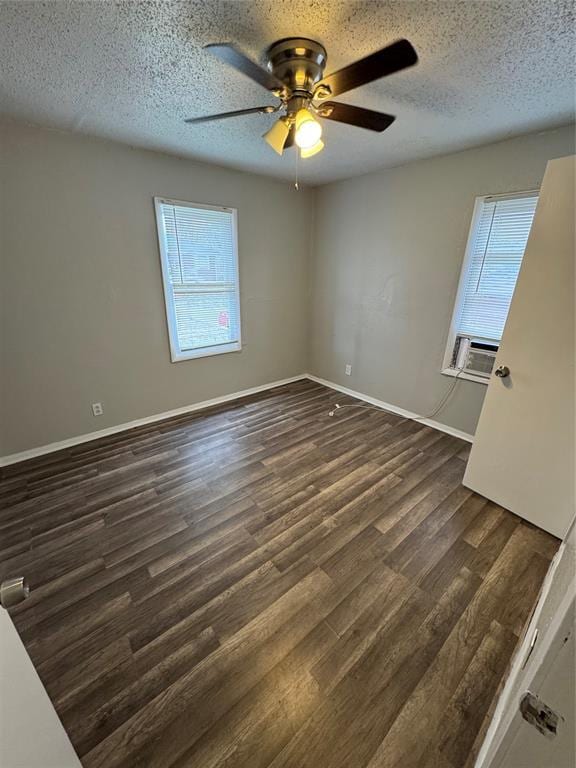 spare room featuring a textured ceiling, dark wood-style flooring, cooling unit, and baseboards