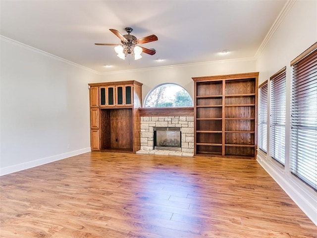 unfurnished living room featuring light wood-style floors, a fireplace, baseboards, and crown molding