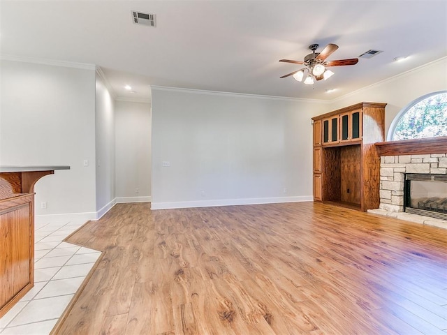 unfurnished living room featuring a ceiling fan, visible vents, a fireplace, and light wood-style flooring