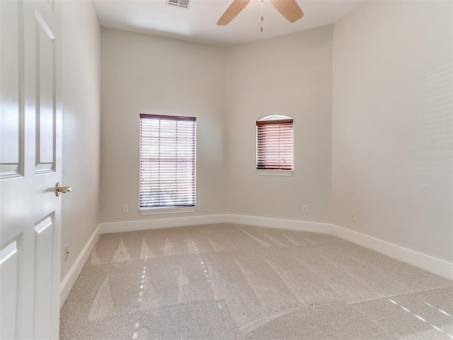 carpeted spare room featuring ceiling fan, visible vents, and baseboards