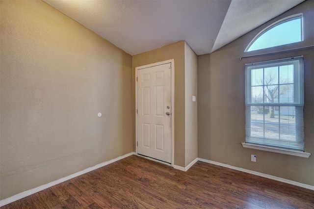 entrance foyer featuring a textured ceiling, baseboards, vaulted ceiling, and wood finished floors