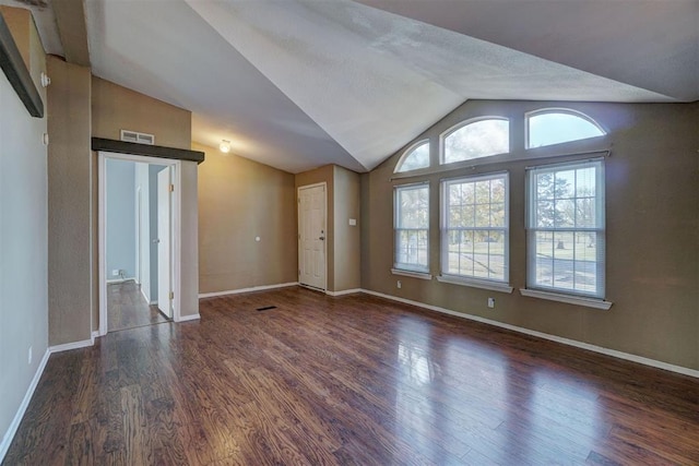 unfurnished room featuring visible vents, vaulted ceiling, baseboards, and wood finished floors