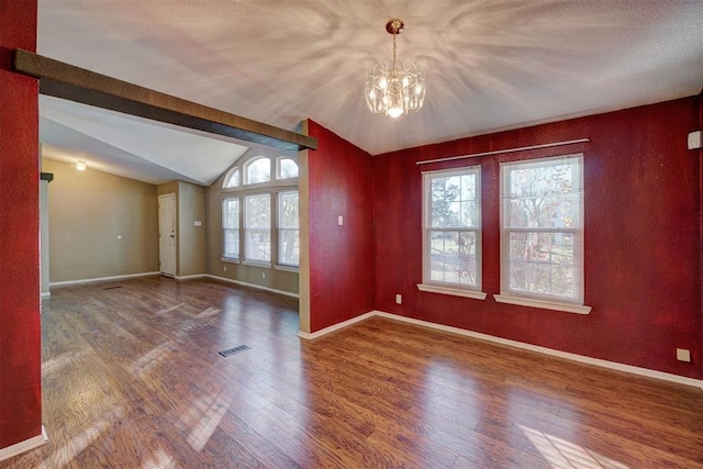 spare room with vaulted ceiling with beams, visible vents, wood finished floors, a chandelier, and baseboards