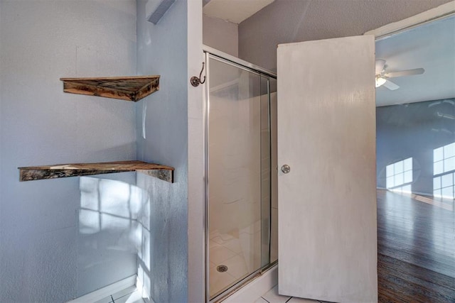 bathroom with a stall shower and a ceiling fan