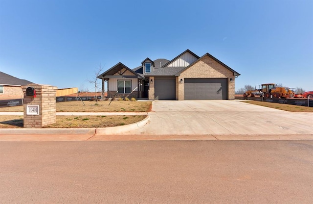 view of front of property with board and batten siding, an attached garage, brick siding, and driveway