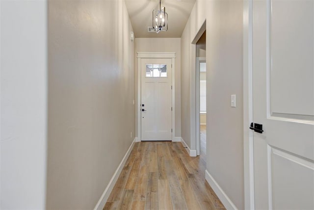 entryway with light wood-style flooring, an inviting chandelier, and baseboards