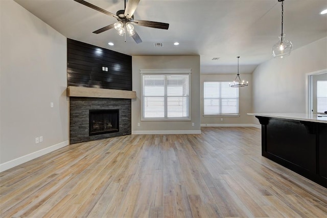 unfurnished living room with visible vents, baseboards, a stone fireplace, and light wood-style flooring