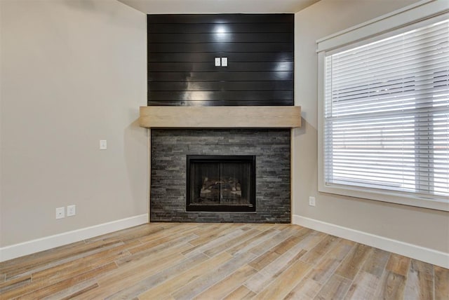 unfurnished living room with a fireplace, baseboards, and wood finished floors