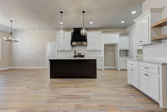 kitchen with tasteful backsplash, open shelves, light countertops, custom range hood, and a sink