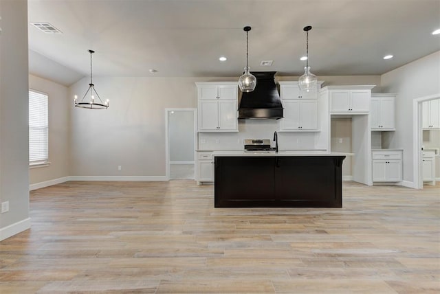 kitchen with white cabinetry, stainless steel range oven, visible vents, and premium range hood