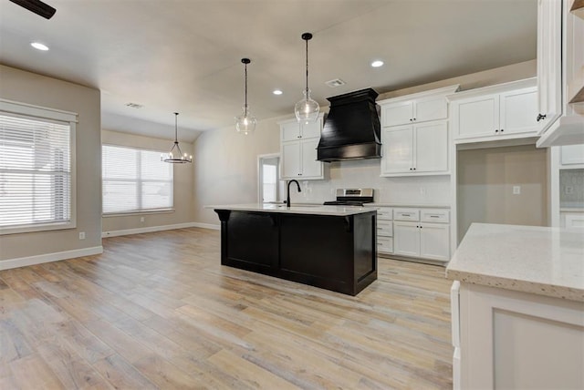 kitchen with custom range hood, light wood finished floors, stainless steel range oven, and white cabinets