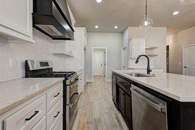 kitchen featuring open shelves, a sink, appliances with stainless steel finishes, white cabinetry, and wall chimney exhaust hood