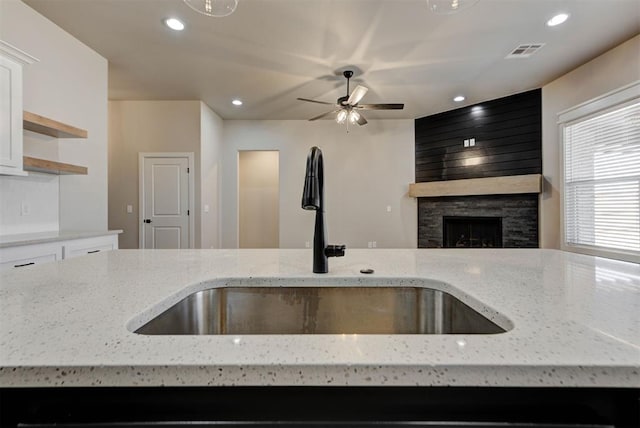 kitchen with visible vents, a sink, open shelves, open floor plan, and a large fireplace