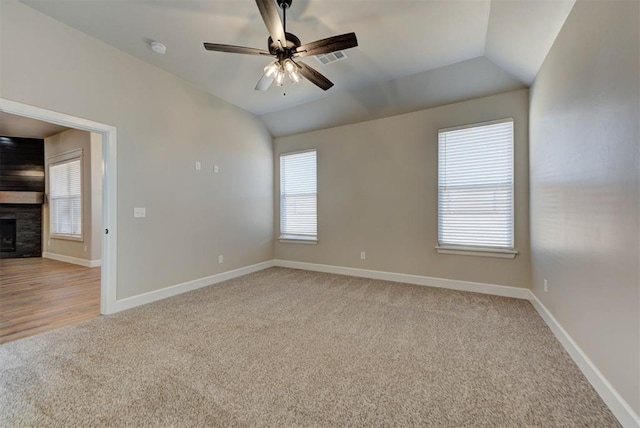 empty room featuring baseboards, lofted ceiling, light colored carpet, and a fireplace