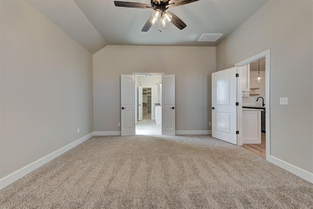 unfurnished bedroom featuring visible vents, light carpet, lofted ceiling, and baseboards