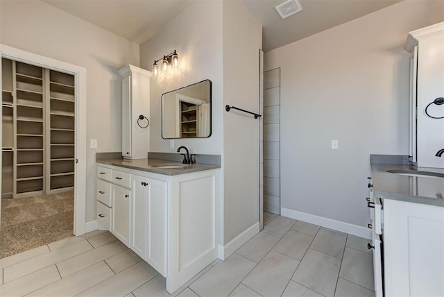 full bathroom with vanity, a spacious closet, baseboards, and visible vents