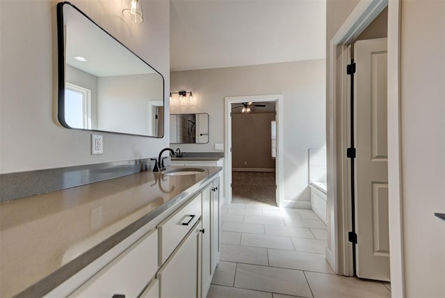 bathroom with a ceiling fan, tile patterned flooring, baseboards, a bath, and vanity