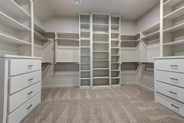 walk in closet with visible vents, lofted ceiling, and carpet