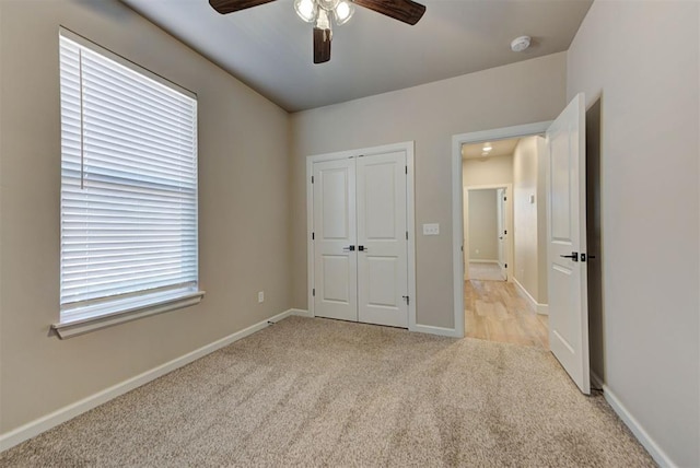 unfurnished bedroom featuring baseboards, light carpet, a closet, and ceiling fan