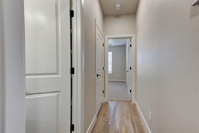 corridor with light wood-style flooring and baseboards