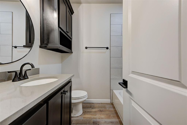 full bath featuring toilet, vanity, baseboards, and wood finished floors