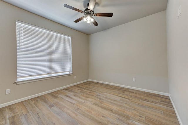 spare room with baseboards, light wood finished floors, and ceiling fan