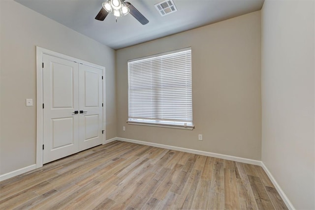 spare room featuring light wood-type flooring, visible vents, baseboards, and ceiling fan