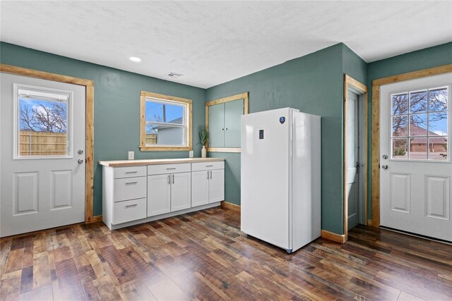 106 N Dewey St, Corn, OK 73024 - kitchen with light countertops, dark wood finished floors, visible vents, freestanding refrigerator, and white cabinets